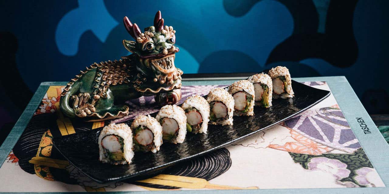 Sushi roll on book next to a dragon figurine. 