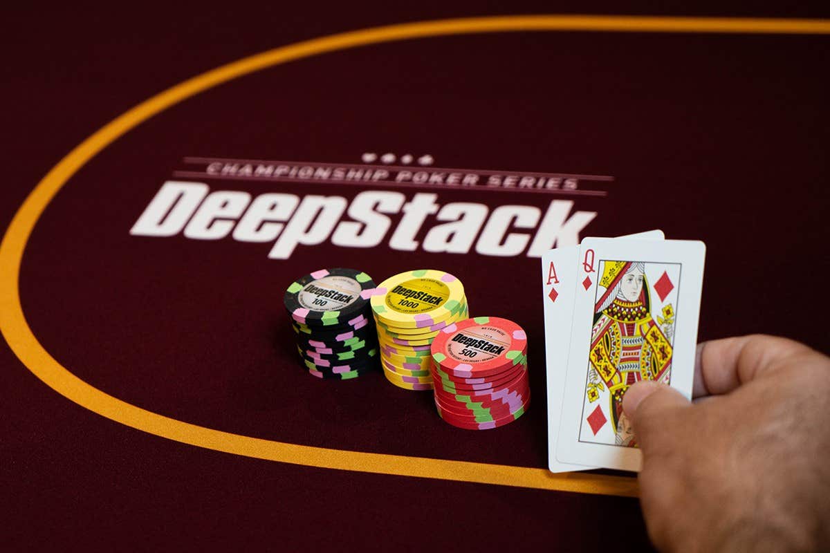Person holding an ace and queen card next to a stack of poker chips
