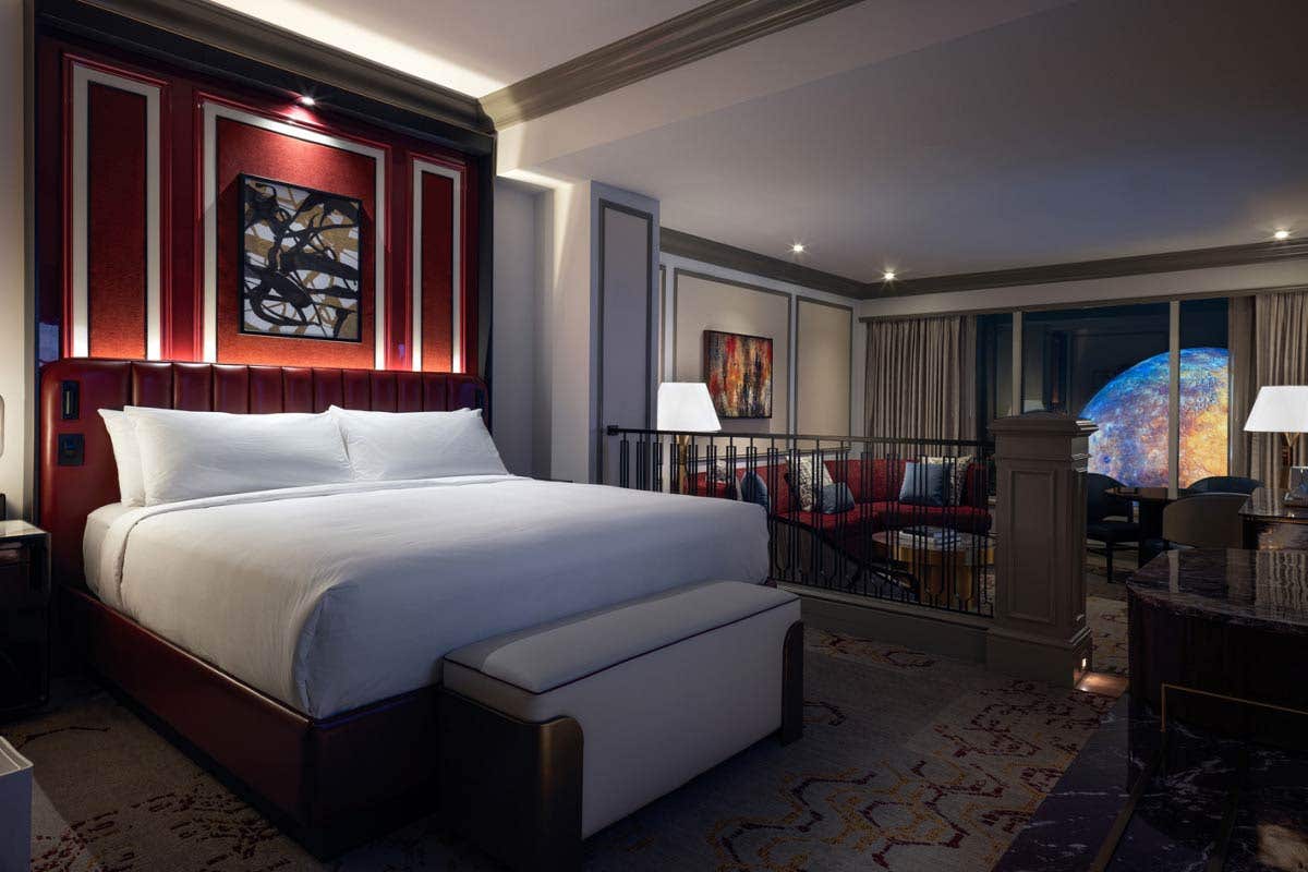 Newly Remodeled Luxury King Suite with a large bed, abstract artwork, and a sitting area with a sofa, overlooking Sphere at The Venetian the window.