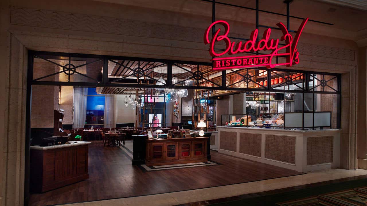 Entrance to Buddy V’s restaurant with an “Buddy V’s lighted sign above.  